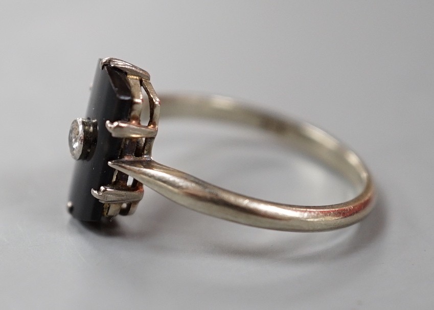 A 9ct white metal, black onyx and single stone diamond set tablet ring, size O, gross weight 2.1 grams.